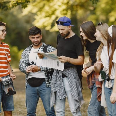 Adventure, travel, tourism, hike and people concept. Group of smiling friends in a forest. Man with a map.
