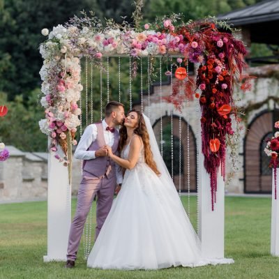 Wedding archway on the backyard and happy wedding couple outdoors before wedding ceremony